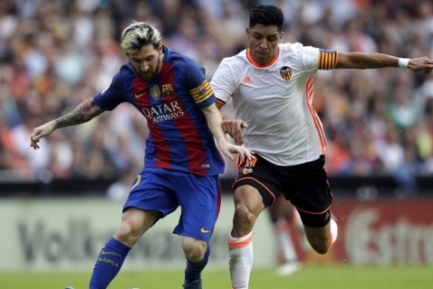 FC Barcelona's Lionel Messi, left, duels for the ball with Valencia's Enzo Perez during the Spanish La Liga soccer match between Valencia and FC Barcelona at the Mestalla stadium in Valencia, Spain, Saturday, Oct. 22, 2016. (AP Photo/Manu Fernandez)