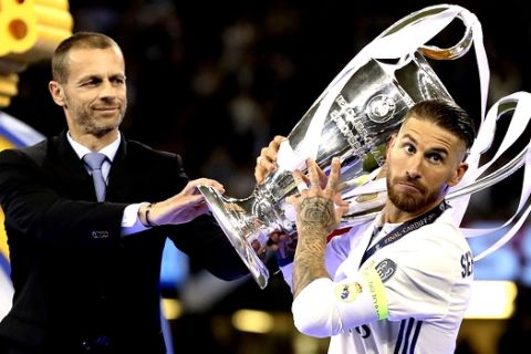 UEFA President Aleksander Ceferin, left, hands the trophy to Real Madrid's Sergio Ramos after the Champions League Final soccer match between Juventus and Real Madrid at the Millennium Stadium in Cardiff, Wales, Saturday, June 3, 2017. (Nick Potts/PA via AP)