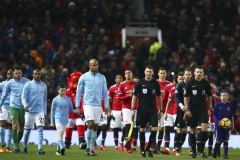 The teams enter the pitch for the English Premier League soccer match between Manchester United and Manchester City, left, at Old Trafford Stadium in Manchester, England, Sunday, Dec. 10, 2017. (AP Photo/Dave Thompson)