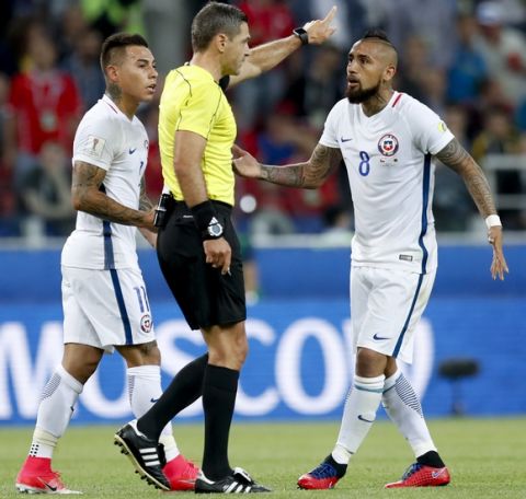 Chile's Arturo Vidal, right, and Eduardo Vargas argue with referee Demir Skomina during the Confederations Cup, Group B soccer match between Cameroon and Chile, at the Spartak Stadium in Moscow, Sunday, June 18, 2017. (AP Photo/Pavel Golovkin)