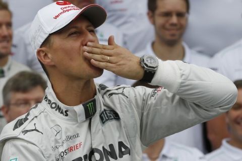Mercedes Grand Prix driver Michael Schumacher of Germany kisses his hand during an official team photo before the Fromula One Brazilian Grand Prix at the Interlagos race track in Sao Paulo, Brazil, Sunday, Nov. 25, 2012. Seven-time world champion Schumacher will be retiring for the second time after the race. (AP Photo/Silvia Izquierdo)