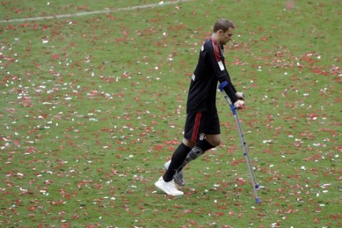 Bayern goalkeeper Manuel Neuer walks on crutches accross the pitch to join a team photo as his team celebrate winning the Bundesliga title after the German first division Bundesliga soccer match between FC Bayern Munich and SC Freiburg at the Allianz Arena stadium in Munich, Germany, Saturday, May 20, 2017. (AP Photo/Matthias Schrader)