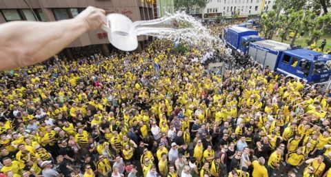 A man pours water on waiting fans for refreshment while standing on his balcony at Borsigplatz square in Dortmund, Germany, Sunday, May 28, 2017. Borussia Dortmund won the German soccer cup final match against Eintracht Frankfurt on Saturday with 2-1. (Guido Kirchner/dpa via AP)