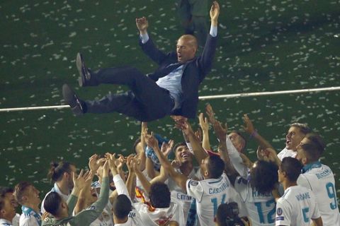 FILE - In this Sunday, May 27, 2018 file photo Real Madrid players lift head coach Zinedine Zidane into the air as they celebrate after winning the Champions League final, at the Santiago Bernabeu stadium in Madrid, Spain. (AP Photo/Francisco Seco, File)