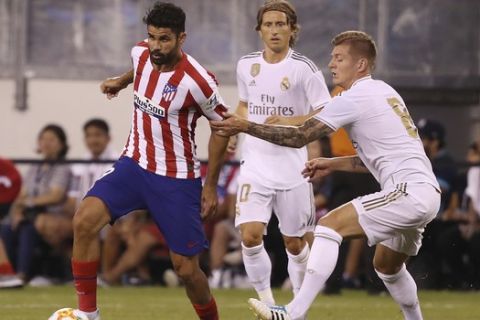 Atletico Madrid forward Diego Costa, left, looks to pass the ball while Real Madrid midfielder Toni Kroos, right, attempts to defend and Real Madrid midfielder Luka Modric watches during the first half of an International Champions Cup soccer match, Friday, July 26, 2019, in East Rutherford, N.J. Atletico Madrid won 7-3. (AP Photo/Steve Luciano)