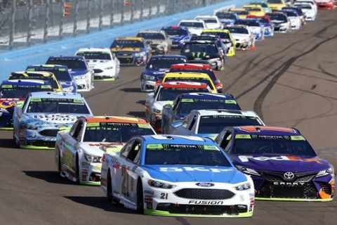 Ryan Blaney (21) leads a group of drivers into the first turn during a NASCAR Cup Series auto race at Phoenix International Raceway, Sunday, Nov. 12, 2017, in Avondale, Ariz. (AP Photo/Ross D. Franklin)