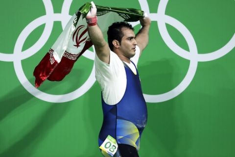 Sohrab Moradi, of Iran, carries an Iranian flag after winning the gold medal in the men's 94kg weightlifting competition at the 2016 Summer Olympics in Rio de Janeiro, Brazil, Saturday, Aug. 13, 2016. (AP Photo/Mike Groll)