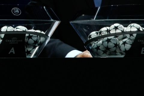 Former Portugal player Luis Figo,  shows the Group E,  as UEFA Director of competitions Giorgio Marchetti looks on during the UEFA Champions League draw in Monaco, Thursday, Aug. 29, 2013. (AP Photo/Claude Paris)