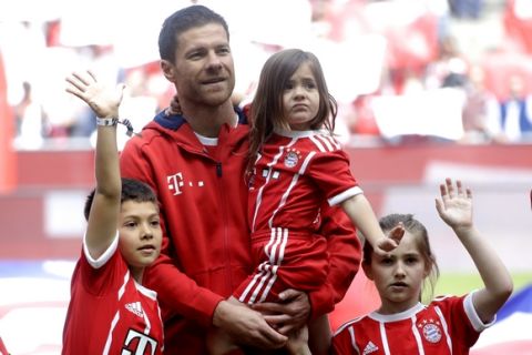 Bayern's Xabi Alonso stands on the pitch with his children during his farewell celebration prior to the German first division Bundesliga soccer match between FC Bayern Munich and SC Freiburg at the Allianz Arena stadium in Munich, Germany, Saturday, May 20, 2017. (AP Photo/Matthias Schrader)