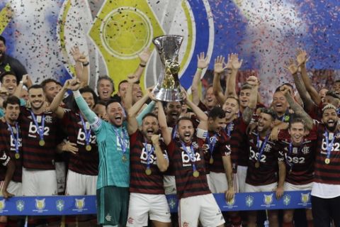 Flamengo's goalkeeper Diego Alves, center left, Diego Ribas, and Everton Ribeiro lift up the trophy as they celebrate with teammates the Brazilian soccer championship at the end of a match against Ceara at the Maracana stadium in Rio de Janeiro, Brazil, Wednesday, Nov. 27, 2019. Days after winning the Copa Libertadores championship, Flamengo won the national championship for the seventh time in its history. (AP Photo/Silvia Izquierdo)
