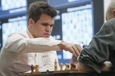 Chess World Champion Magnus Carlsen, left, from Norway holds a figure during a game of chess against Russia's Nikolai Vlassov, right, during the World Rapid and Blitz Chess Championships in St. Petersburg, Russia, Wednesday, Dec. 26, 2018. (AP Photo/Dmitri Lovetsky)