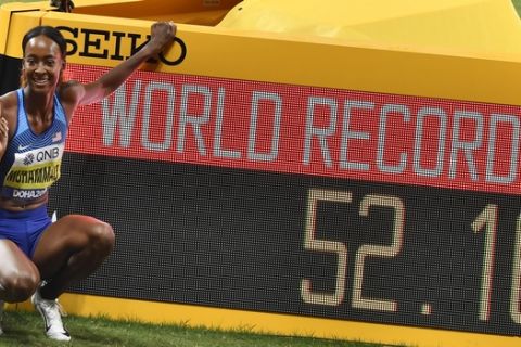 Gold medallist Dalilah Muhammad, of the United States, poses next to the scoreboard after setting a new world record in the women's 400 meter hurdles final at the World Athletics Championships in Doha, Qatar, Friday, Oct. 4, 2019. (AP Photo/Martin Meissner)