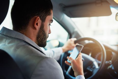 Cropped shot of a man using his phone while driving