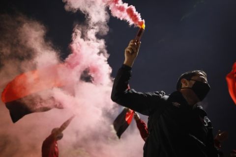A man wearing a protective face mask holds a flare during a caravan organized by the soccer club fans of Newell's Old Boys in the hometown of Leonel Messi, in Rosario, Argentina, Thursday, Aug. 27, 2020. Fans hope to lure him home following his announcement that he wants to leave Barcelona F.C. after nearly two decades with the Spanish club. (AP Photo/Natacha Pisarenko)