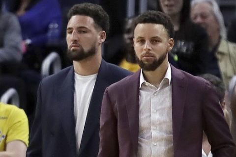 Golden State Warriors' Klay Thompson, left, and Stephen Curry watch from the bench during the second half of an NBA basketball game against the Denver Nuggets, Thursday, Jan. 16, 2020, in San Francisco. (AP Photo/Ben Margot)