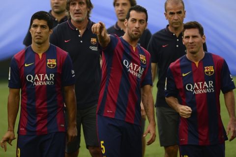 FC Barcelona's Luis Suarez, from Uruguay, left, looks on near of Barcelona's Sergio Busquets, second left, and Lionel Messi, from Argentina, during his official presentation prior of the Joan Gamper trophy match Between FC Barcelona and Leon at the Camp Nou in Barcelona, Spain, Monday, Aug. 18, 2014. (AP Photo/Manu Fernandez)