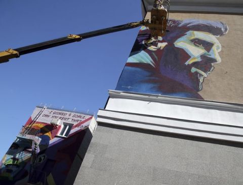Russian graffiti artists of the SuperNovaNet team make a mural of Argentina's Lionel Messi as their older project with Portugal's Cristiano Ronaldo portrait is seen next to the hotel of Argentina team during the 2018 soccer World Cup in Kazan, Russia, Friday, June 29, 2018. (AP Photo/Thanassis Stavrakis)