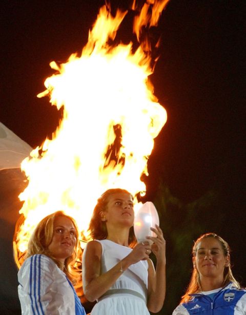 Ten year-old Fotini Papaleonidopoulou holds a lantern in the shape of a seed after lighting it from the Olympic cauldron, background, during the closing ceremony for the 2004 Olympic Games at the Olympic stadium in Athens, Greece, Sunday, Aug. 29, 2004. (AP Photo/Hasan Sarbakhshian)