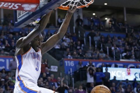 Oklahoma City Thunder forward Jerami Grant (9) hangs from the basket in front of Sacramento Kings forward Garrett Temple, right, following a dunk in the second half of an NBA basketball game in Oklahoma City, Monday, March 12, 2018. (AP Photo/Sue Ogrocki)