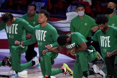 Members of the Boston Celtics lock arms as they listen to the national anthem before an NBA conference final playoff basketball game against the Miami Heat on Thursday, Sept. 17, 2020, in Lake Buena Vista, Fla. (AP Photo/Mark J. Terrill)