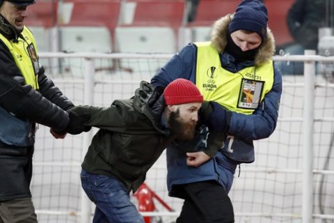 Security take out a fan from the field during a Group G Europa League soccer match between Spartak Moscow and Rapid Wien at the Spartak Stadium in Moscow, Russia, Thursday, Nov. 29, 2018. (AP Photo/Pavel Golovkin)
