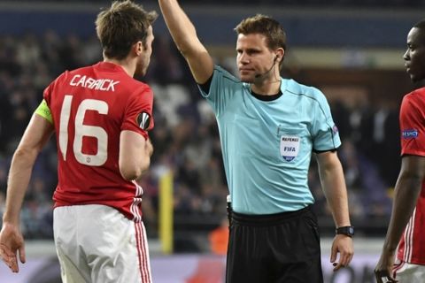 Referee Felix Brych shows a yellow card to United's Michael Carrick during a Europa League quarterfinal first leg soccer match between Anderlecht and Manchester United at the Constant Vanden Stock stadium in Brussels, Thursday, April 13, 2017. (AP Photo/Geert Vanden Wijngaert)