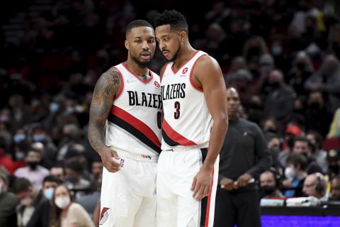 Portland Trail Blazers guard Damian Lillard, left, speaks with guard CJ McCollum during the second half of the team's NBA basketball game against the Los Angeles Lakers in Portland, Ore., Saturday, Nov. 6, 2021. The Blazers won 105-90. (AP Photo/Steve Dykes)
