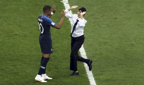 A woman who invaded the pitch approaches France's Kylian Mbappe during the final match between France and Croatia at the 2018 soccer World Cup in the Luzhniki Stadium in Moscow, Russia, Sunday, July 15, 2018. (AP Photo/Thanassis Stavrakis)