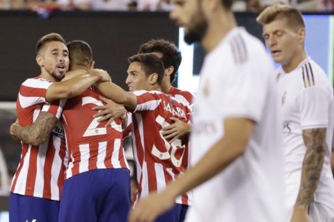 Atletico Madrid's Hector Herrera (16) hugs Vitolo (20) after Vitolo scored a goal as Real Madrid players react during the second half of a soccer match Friday, July 26, 2019, in East Rutherford, N.J. (AP Photo/Frank Franklin II)