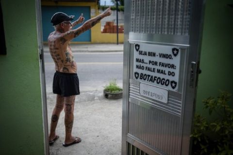 TO GO WITH AFP STORY by Javier Tovar
Brazilian football club Botafogo fan Delneri Martins Viana, a 69-year-old retired soldier, gestures at neighbours outside his house in Rio de Janeiro, Brazil, on January 18, 2014. Delneri has 83 tattoos on his body dedicated to Botafogo and describes himself as the club's biggest fan.   AFP PHOTO / YASUYOSHI CHIBA