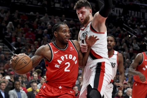 Toronto Raptors forward Kawhi Leonard, left, drives to the basket on Portland Trail Blazers center Jusuf Nurkic, right, during the first half of an NBA basketball game in Portland, Ore., Friday, Dec. 14, 2018. (AP Photo/Steve Dykes)