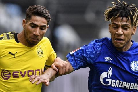 Dortmund's Achraf Hakimi, left, and Schalke's Jean-Clair Todibo hold each other while fighting for the ball during the German Bundesliga soccer match between Borussia Dortmund and Schalke 04 in Dortmund, Germany, Saturday, May 16, 2020. The German Bundesliga becomes the world's first major soccer league to resume after a two-month suspension because of the coronavirus pandemic. (AP Photo/Martin Meissner, Pool)