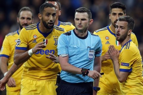 Juventus players complain to Referee Michael Oliver, center, for a penalty shot for Real, during a Champions League quarter-final, 2nd leg soccer match between Real Madrid and Juventus at the Santiago Bernabeu stadium in Madrid, Spain, Wednesday, April 11, 2018. (AP Photo/Paul White)
