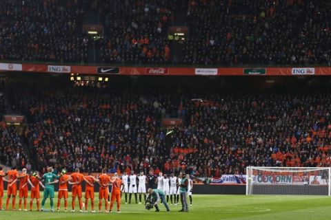 The Belgian flag is seen on a screen as players of the Dutch, in orange, and French soccer squads observe a minute of silence to commemorate the victims of the Brussels attacks prior a international friendly soccer match between The Netherlands and France at the ArenA stadium in Amsterdam, Netherlands, Friday, March 25, 2016. (AP Photo/Peter Dejong)