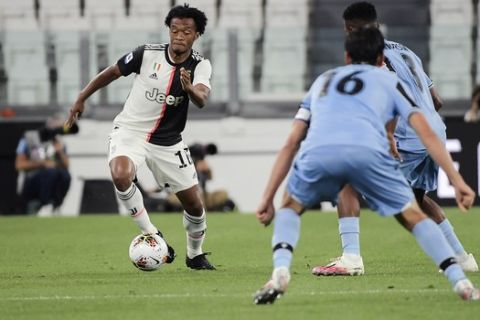 Juventus' Juan Cuadrado, left, runs with the ball during the Italian Serie A soccer match between Juventus and Lazio at the Allianz stadium in Turin, Italy, Monday, July 20, 2020. (Marco Alpozzi/LaPresse via AP)