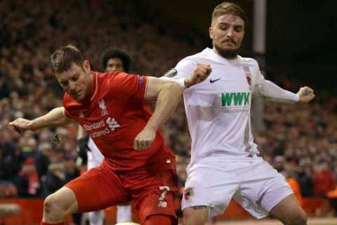 Liverpool's James Milner, left, and FC Augsburg's Kostas Stafylidis battle for the ball during the Europa League round of 32 second leg soccer match between Liverpool and FC Augsburg in Liverpool, England, Thursday Feb. 25, 2016. (AP Photo/Clint Hughes)