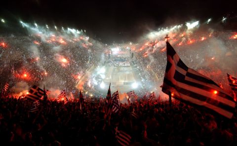 Tens of thousands of fans wave Greek flags and flares at the all-marble Panathenian stadium, where the first modern Olympics were held in 1896, to welcome Greece's national soccer team after it won the Euro 2004 championships, in Athens on Monday, July 5, 2004. (AP Photo/Petros Giannakouris)  