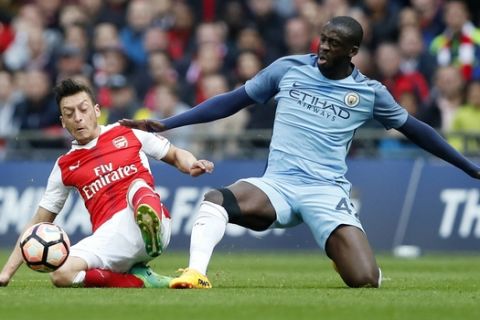 Arsenal's Mesut Ozil, left, vies for the ball with Manchester City's Yaya Toure during the English FA Cup semifinal soccer match between Arsenal and Manchester City at Wembley stadium in London, Sunday, April 23, 2017. (AP Photo/Kirsty Wigglesworth)