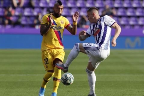 Barcelona's Arturo Vidal, left, and Valladolid's Raul Garcia challenge for the ball during the Spanish La Liga soccer match between Valladolid and FC Barcelona at the Jose Zorrilla stadium in Valladolid, Spain, Saturday, July 11, 2020. (AP Photo/Manu Fernandez)