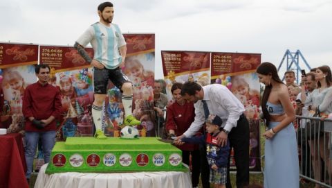 The major of Bronnitsy helps a boy cut a cake to mark Lionel Messi's birthday near Argentina training camp base at the 2018 World Cup in Bronnitsy, Russia, Sunday, June 24, 2018. Wth a cake sculpture and a music festival the town of Bronnitsy celebrated the striker's 31st birthday.(AP Photo/Ricardo Mazalan)