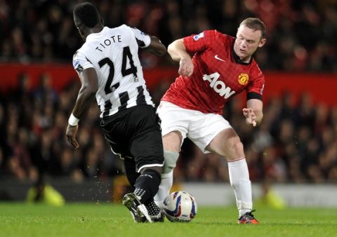 Manchester United's Wayne Rooney, right is tackled by Newcastle's United's  Cheick Tiote, left during their English League Cup third round match at Old Trafford in Manchester, England, Wednesday Sept. 26, 2012. (AP Photo/Clint Hughes)  