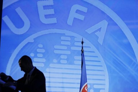 UEFA President-elect Aleksander Ceferin, right, and UEFA  Chief of Press Pedro Pinto are silhouetted  against an UEFA logo , at the end of a vote for an new UEFA president, in Athens, on Wednesday, Sept. 14, 2016. UEFA elected Aleksander Ceferin to succeed Michel Platini as president on Wednesday, replacing one of the greats of soccer with a largely unknown Slovenian lawyer to lead the European game. (AP Photo/Thanassis Stavrakis)