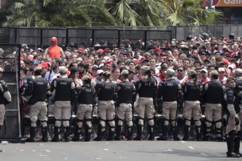 Security forces stand guard outside outside Antonio Vespucio Liberti stadium where River Plate soccer fans  gather before the announcement that their team's final Copa Libertadores match against rival Boca Juniors is suspended for a second day in a row in Buenos Aires, Argentina, Sunday, Nov. 25, 2018. In one of the most embarrassing weekends in South American football history, the Copa Libertadores final was once more postponed on Sunday. The same decision was made on Saturday after Boca's bus was attacked by River fans.  (AP Photo/Diego Martinez)