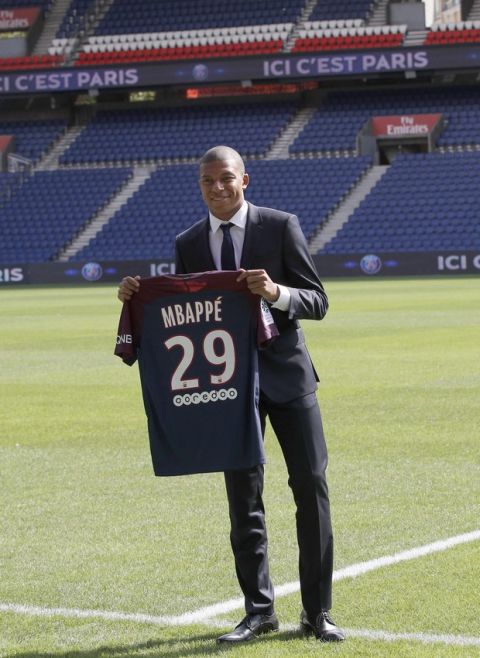 French soccer player Kylian Mbappe poses with his team shirt following a press conference in Paris, Wednesday, Sept. 6, 2017. Mbappe is a young man in a big hurry and wants to "win everything" with his new club Paris Saint-Germain. (AP Photo/Christophe Ena)