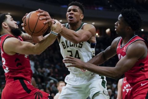 Milwaukee Bucks' Giannis Antetokounmpo is fouled as he drives between Toronto Raptors' Fred VanVleet and OG Anunoby during the second half of an NBA basketball game Saturday, Nov. 2, 2019, in Milwaukee. The Bucks won 115-105. (AP Photo/Morry Gash)