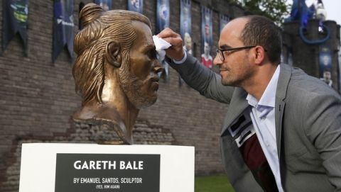 Artist Emanuel Santos, wipes a bust of Real Madrid and Wales soccer player Gareth Bale that he created, after it was placed on display in Cardiff, Wales Wednesday May 31, 2017, ahead of this weekend's Champions League final between Real Madrid and Juventus.  Santos is the artist behind the controversial recent Cristiano Ronaldo bust at Madeira airport. (Geoff Caddick/PA via AP)