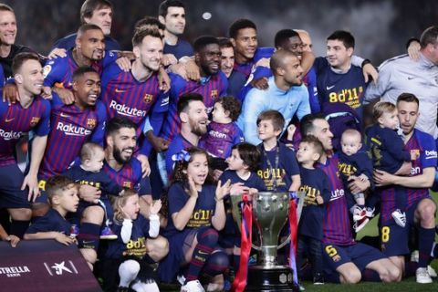 FC Barcelona players, with their children, pose with their trophy after winning the Spanish League title, at the end of the Spanish La Liga soccer match between FC Barcelona and Levante at the Camp Nou stadium in Barcelona, Spain, Saturday, April 27, 2019. Barcelona clinched the Spanish La Liga title, with three matches to spare, after it defeated Levante 1-0. (AP Photo/Manu Fernandez)
