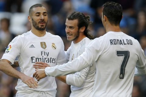 Real Madrid's Karim Benzema, left, celebrates with teammates Cristiano Ronaldo, right, and Gareth Bale after scoring their side's third goal against Getafe during the Spanish La Liga soccer match between Real Madrid and Getafe at the Santiago Bernabeu stadium in Madrid, Saturday, Dec. 5, 2015. Benzema scored twice and Ronaldo and Bale scored once each in Real Madrid's 4-1 victory. (AP Photo/Francisco Seco)