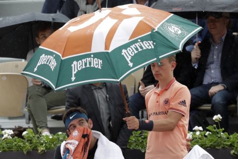 Argentina's Juan Martin Del Potro sits under an umbrella as he plays Croatia's Marin Cilic during their quarterfinal match of the French Open tennis tournament at the Roland Garros stadium, Wednesday, June 6, 2018 in Paris. Play is being delayed by rain during the French Open men's quarterfinals. (AP Photo/Alessandra Tarantino)
