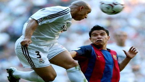 Real Madrid's Roberto Carlos, left, heads the ball clear as Barcelona's Javier Saviola, of Argentina, comes charging in during a Spanish league soccer match in Madrid, Sunday April 25, 2004. (AP Photo/Paul White)